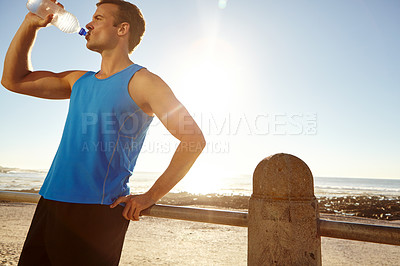 Buy stock photo Shot of a man drinking a bottle of water and taking a break after a long jog 