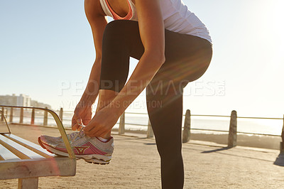 Buy stock photo Shot of an athletic woman tying her shoe laces on a bench 
