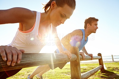 Buy stock photo A young couple doing push ups against a wooden fence