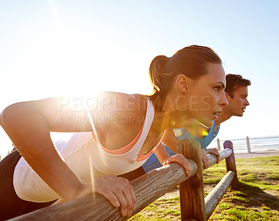 Buy stock photo A young couple doing push ups against a wooden fence