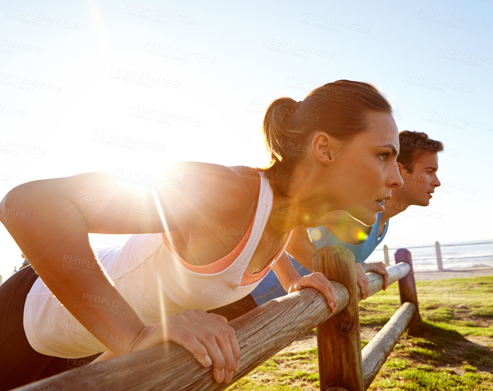 Buy stock photo A young couple doing push ups against a wooden fence