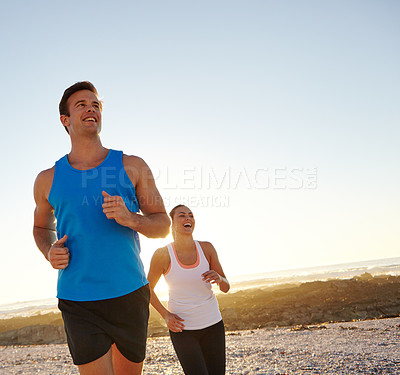 Buy stock photo Shot of a young couple jogging together on the beach