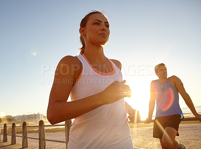 Buy stock photo Shot of a beautiful woman jogging pass a man on the promenade