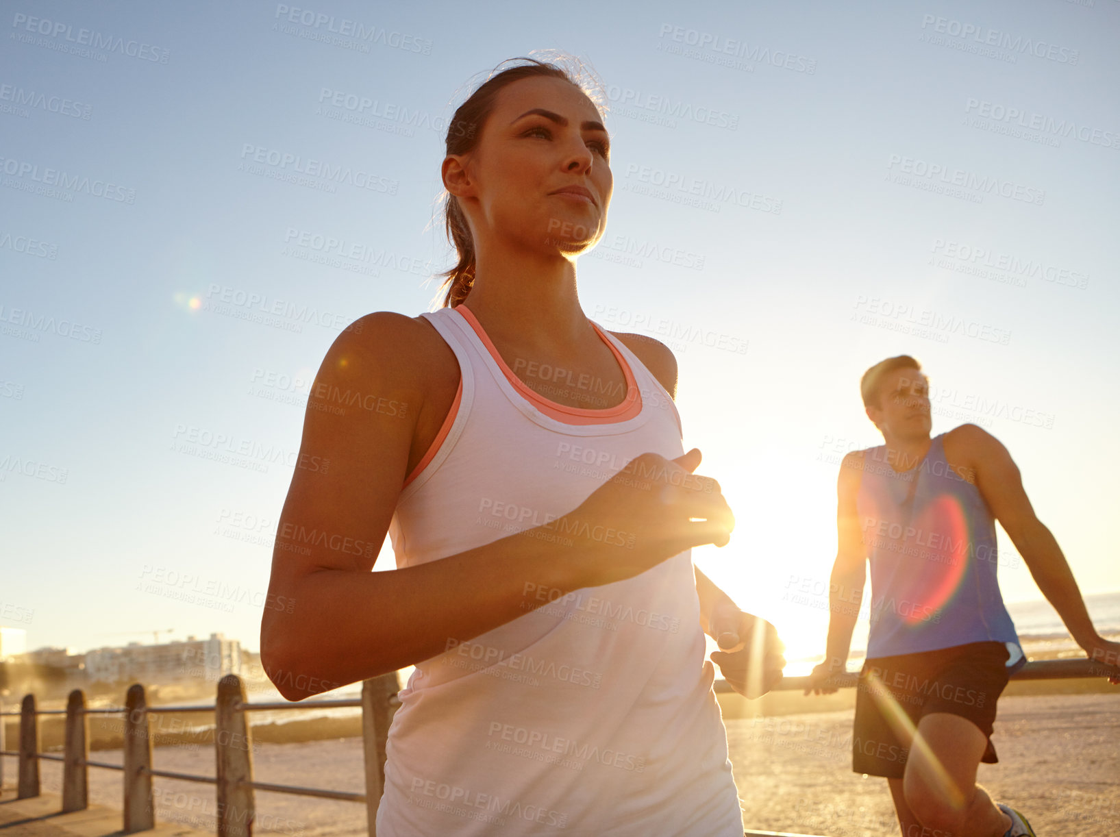 Buy stock photo Shot of a beautiful woman jogging pass a man on the promenade