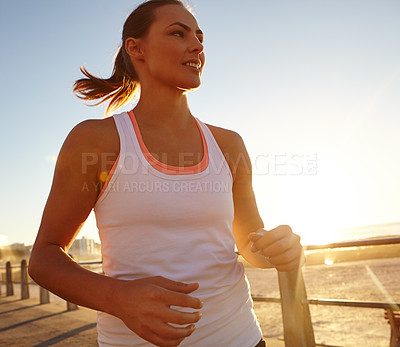 Buy stock photo Shot of an attractive woman jogging on the promenade