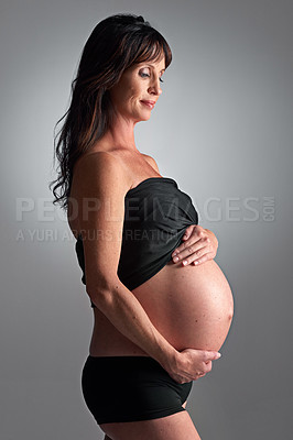 Buy stock photo Studio, pregnant and woman with hands for stomach, growth and health of baby, body and glow with cosmetics. Grey background, mom and child in belly or abdomen, shine and skincare for parent and skin