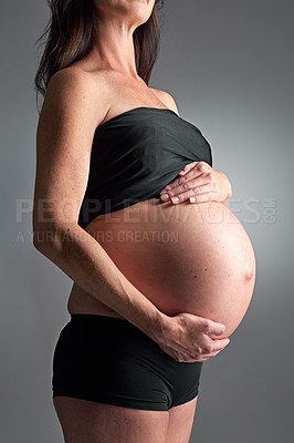 Buy stock photo Studio, pregnant and person with hands for stomach, growth and health of baby, body and glow with cosmetics. Grey background, mom and child in belly or abdomen, shine and skincare for parent and skin