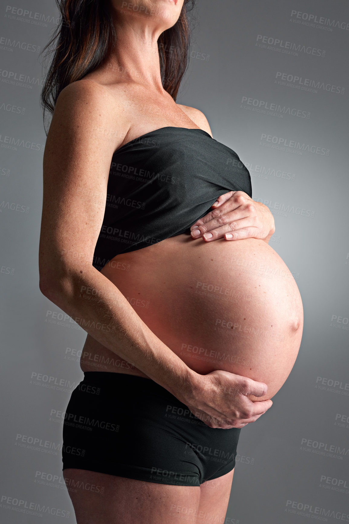 Buy stock photo Studio, pregnant and person with hands for stomach, growth and health of baby, body and glow with cosmetics. Grey background, mom and child in belly or abdomen, shine and skincare for parent and skin