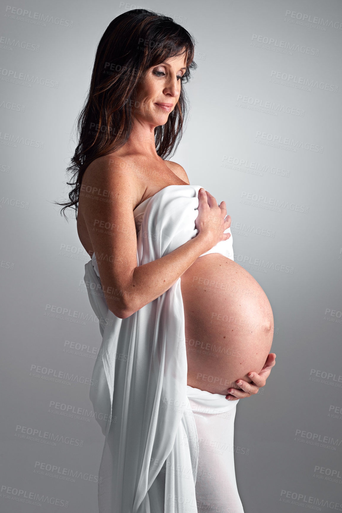 Buy stock photo Studio, pregnant and woman with support for stomach, growth and parent of baby, body and glow with cosmetics. Grey background, mom and child in belly or abdomen, shine and skincare for health of skin