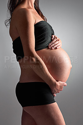 Buy stock photo Studio, pregnant and person with stomach, healthy and growth of baby, body and glow with cosmetics. Grey background, mom and child in belly or abdomen, shine and skincare for woman and love of parent