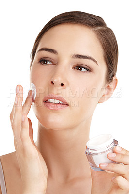 Buy stock photo Cropped shot of a beautiful young woman applying moisturizer against a white background