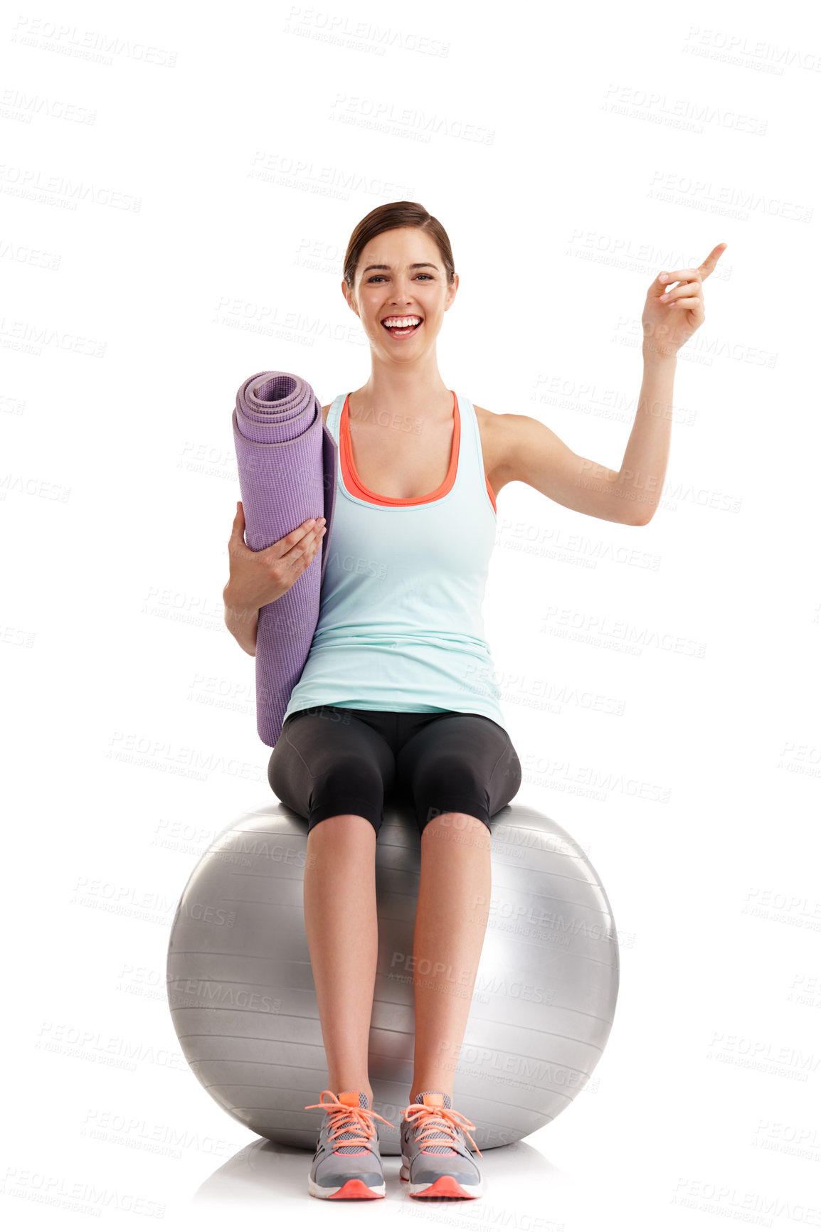 Buy stock photo Shot of a young woman pointing at something in a studio with her yoga mat and exercise ball