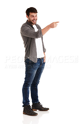 Buy stock photo Full length studio shot of a smiling young man pointing to something funny