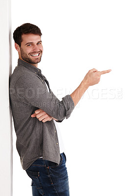 Buy stock photo Studio shot of a smiling young man pointing at copyspace to the right