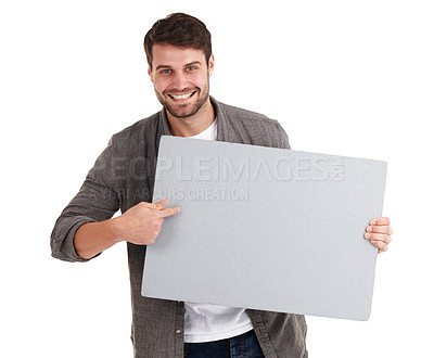 Buy stock photo Studio portrait of a smiling young man holding a blank poster and pointing to it excitedly