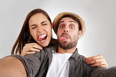 Buy stock photo Self portrait of a happy young couple in studio pulling silly faces