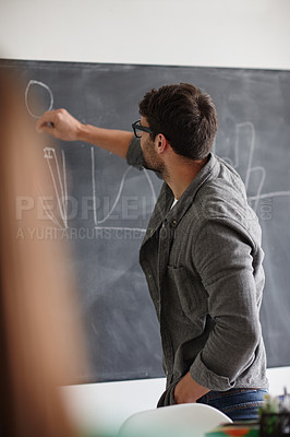 Buy stock photo Shot of a young man writing information on a blackboard