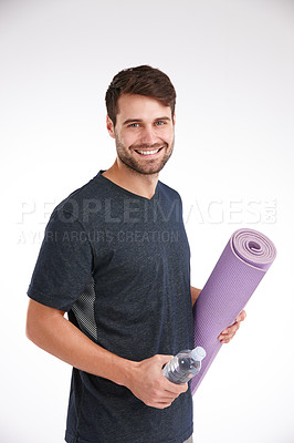 Buy stock photo Studio portrait of a smiling young man holding a yoga mat and a water bottle