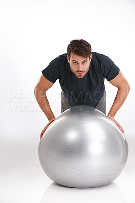 Buy stock photo Studio shot of a young man doing pushups on an exercise ball
