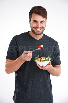 Buy stock photo Studio portrait of a smiling young man eating salad from a bowl
