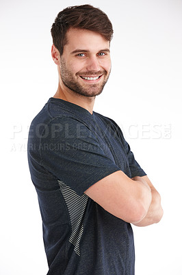 Buy stock photo Studio shot of a smiling young man standing with his arms folded