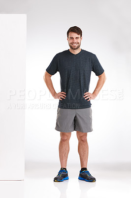 Buy stock photo Studio shot of a smiling young man standing casually with his hands on his hips