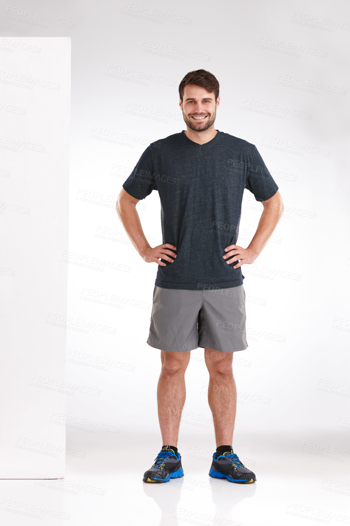 Buy stock photo Studio shot of a smiling young man standing casually with his hands on his hips