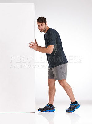 Buy stock photo Studio shot of a serious young man moving a blank billboard