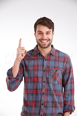 Buy stock photo Studio shot of a smiling young man pointing directly above him to copyspace