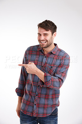 Buy stock photo Studio portrait of a smiling young man pointing at copyspace to the left