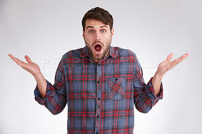 Buy stock photo Studio portrait of a young man holding up his hands and looking surprised