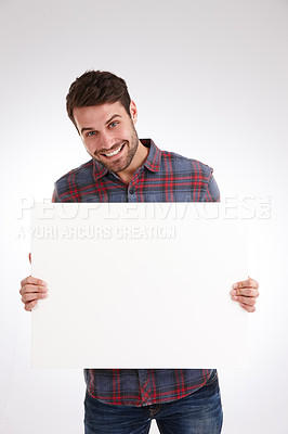 Buy stock photo Studio shot of a smiling young man holding a blank white poster