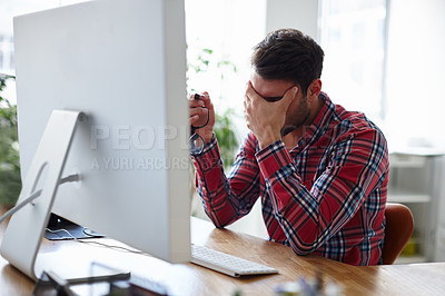 Buy stock photo Shot of a casual young designer holding his head in despair