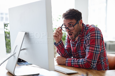 Buy stock photo Shot of a young designer looking at his computer screen with shock and disbelief