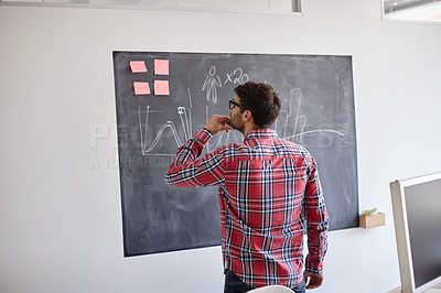 Buy stock photo Rearview shot of a designer contemplating graphs on a blackboard