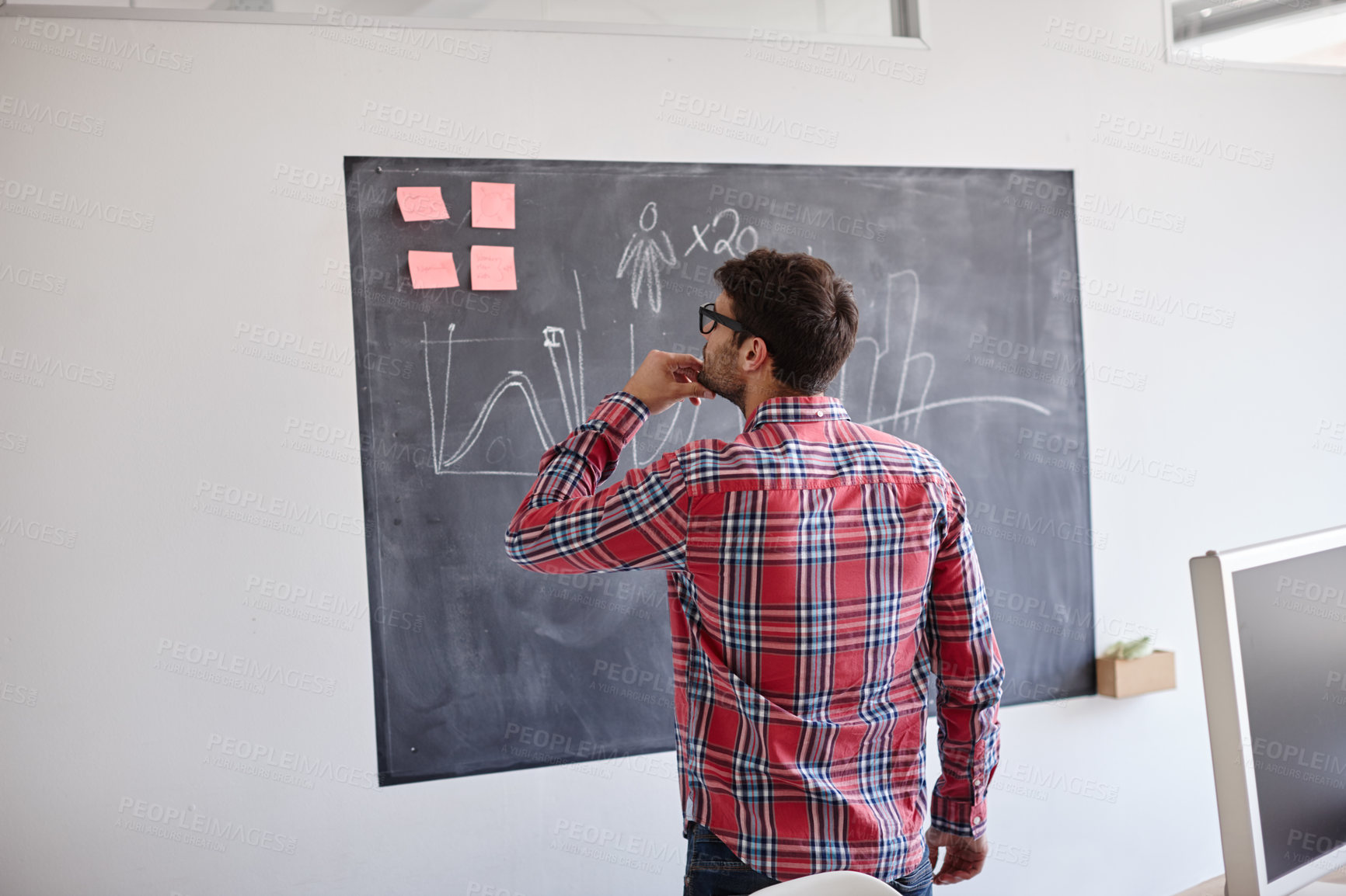 Buy stock photo Rearview shot of a designer contemplating graphs on a blackboard