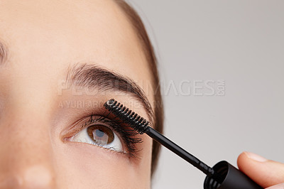 Buy stock photo Closeup shot of a young woman applying mascara in studio