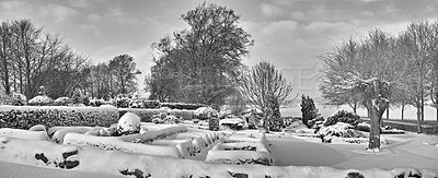 Buy stock photo Gloomy graveyard in a monochrome winter landscape. Snow covered gravestones against a grey cloudy sky. Black and white empty frosted cemetery and frozen trees in greyscale. Snowfall in Scandinavia