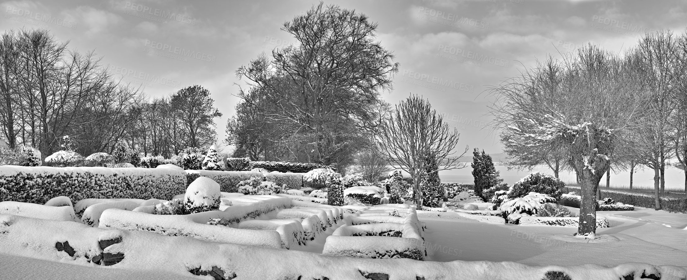 Buy stock photo Gloomy graveyard in a monochrome winter landscape. Snow covered gravestones against a grey cloudy sky. Black and white empty frosted cemetery and frozen trees in greyscale. Snowfall in Scandinavia