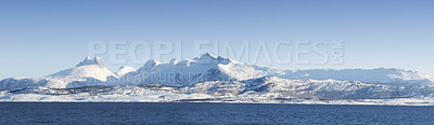 Buy stock photo Landscape of mountains with snow and glaciers against blue sky. Empty hilltops with white snowfall melting into ocean water. A snowy island on a sunny day. Impact of global warming and climate change