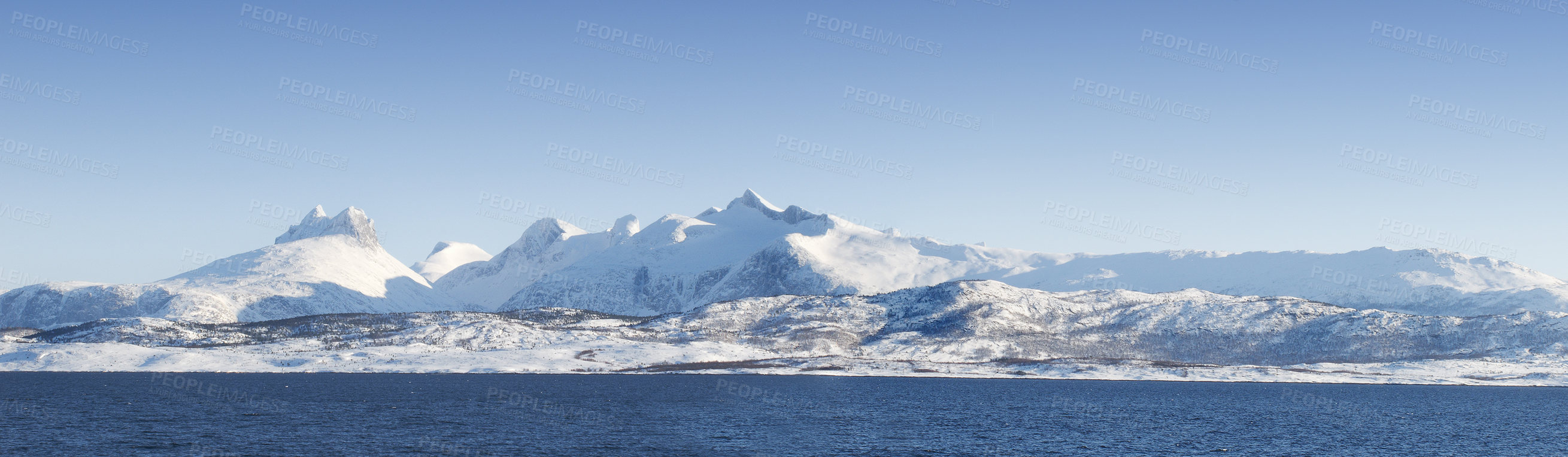 Buy stock photo Landscape of mountains with snow and glaciers against blue sky. Empty hilltops with white snowfall melting into ocean water. A snowy island on a sunny day. Impact of global warming and climate change