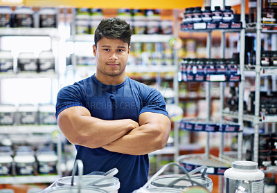 Buy stock photo Shot of a muscular young man in the supplement section of a pharmacy