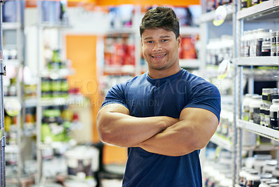 Buy stock photo Shot of a muscular young man in the supplement section of a pharmacy