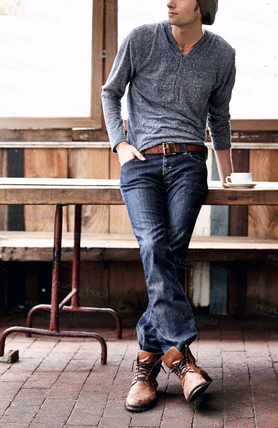 Buy stock photo Man, jeans and vintage coffee shop with fashion, drink and relax with shoes, espresso and hands in pockets. Student guy, retro cafe and clothes with matcha, tea cup and leather boots on brick floor