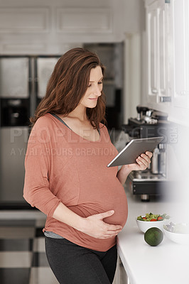Buy stock photo Cropped shot of a pregnant woman using her tablet in the kitchen
