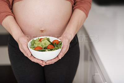 Buy stock photo Cropped shot of a young pregnant woman holding a salad in the kitchen