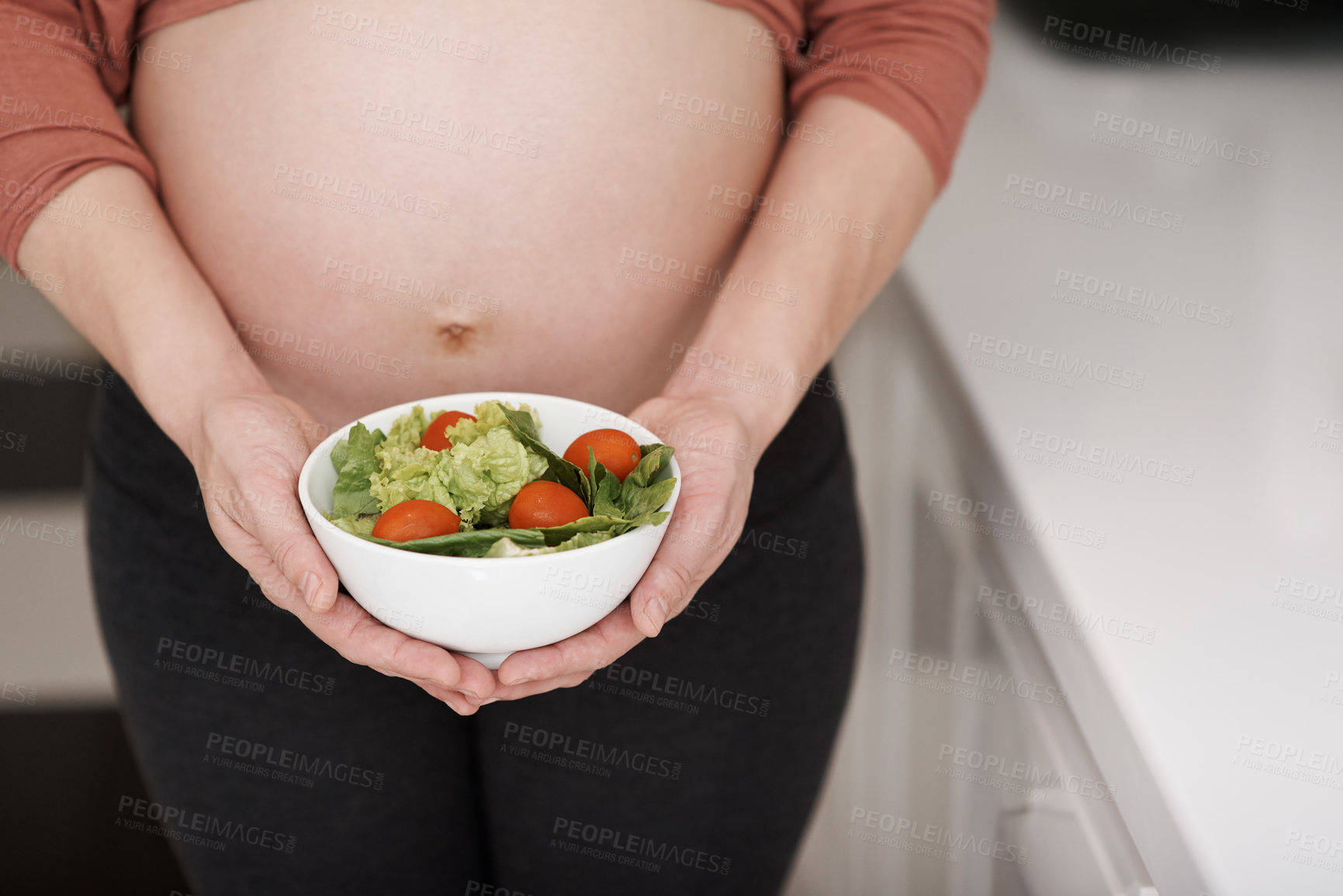 Buy stock photo Salad, pregnancy and belly of woman in kitchen for food with healthy, wellness and nutrition diet. Vegetables, vitamins and pregnant female person with fresh meal for lunch for prenatal care at home.