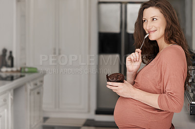 Buy stock photo Cropped shot of a young pregnant woman eating a cupcake in the kitchen
