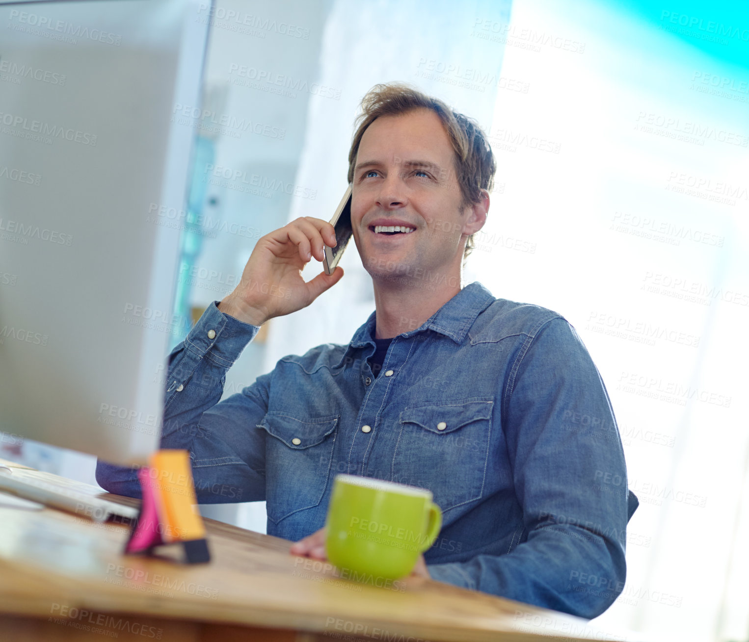 Buy stock photo Shot of a designer talking on a cellphone while working on a computer in an office