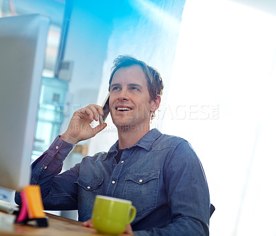 Buy stock photo Shot of a designer talking on a cellphone while working on a computer in an office
